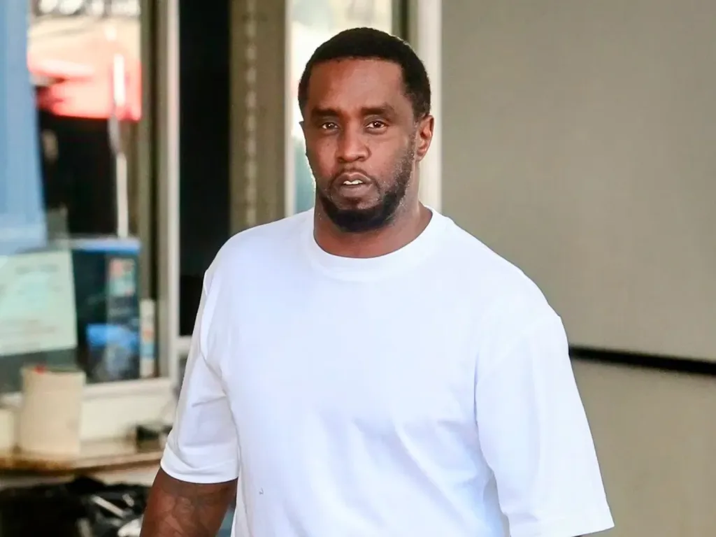 Sean «Diddy» Combs con camiseta blanca y barba corta caminando frente a un local